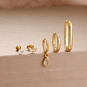 Detailed close-up of gold-plated earring set featuring zircon studs and polished hoops