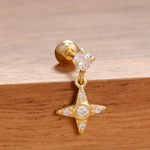 Macro de pendiente de estrella en acero inoxidable dorado con circonitas sobre madera