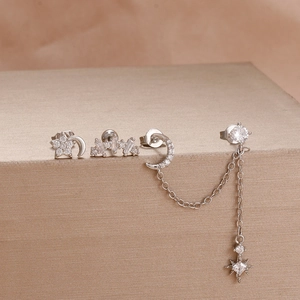 Detail of silver earring set with star and moon studs featuring white zirconia stones