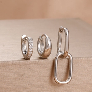 Detailed view of three-piece silver zircon hoop earrings set on a metallic stand