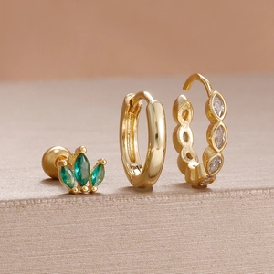 Detaillierte Makroansicht eines dreiteiligen Gold-Ohrringsets mit grünen Steinen