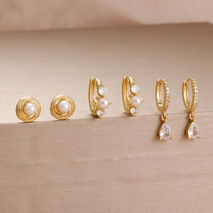 Detailansicht goldener Ohrringe mit Perlen und tropfenförmigen Zirkonia-Anhängern