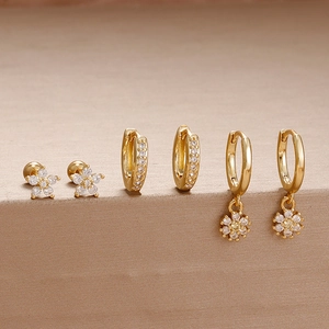 Detailliertes Set aus drei goldenen Edelstahlohrringen mit funkelnden Zirkon-Blumenanhängern