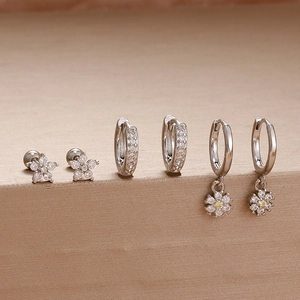 Detailansicht silberner Piercing-Ohrringe mit Blumensteckern und Zirkonia-Creolen
