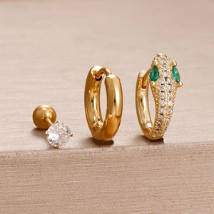 Détail macro du set de boucles d'oreilles serpent dorées avec diamants et yeux verts