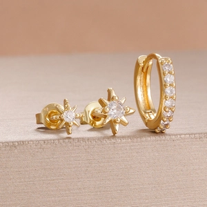 Détail macro de boucles d'oreilles étoile dorées et ensemble créole avec cristaux