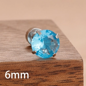 Détail d'un piercing en zircone bleu clair 6mm avec monture à quatre griffes