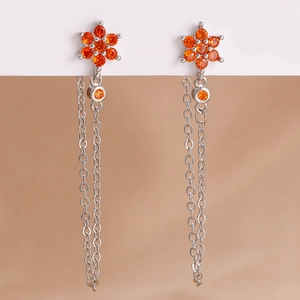 Dettaglio macro degli orecchini a fiore in argento con nappe e zirconi arancioni