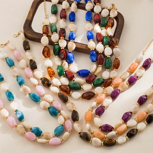 Dettaglio di collane con perle in resina multicolore e distanziatori metallici dorati