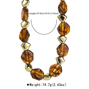 Chunky necklace detail showing amber marble beads and golden geometric metallic accents