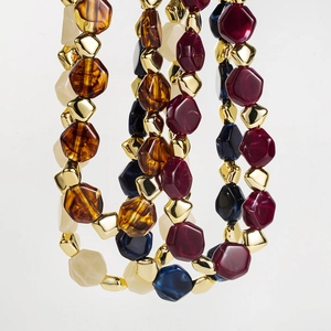Close-up of retro beaded necklace featuring multicolored geometric facets and golden beads