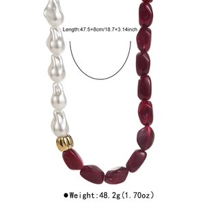 Détail de collier en perles baroques avec perles de résine rouges et boule dorée ondulée