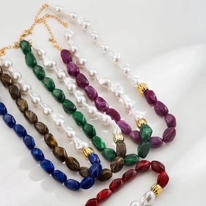 Détail de colliers en perles de résine baroque multicolores avec des accents en métal doré