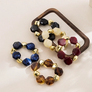 Detail of four-piece colorful geometric resin bead bracelets with gold accents