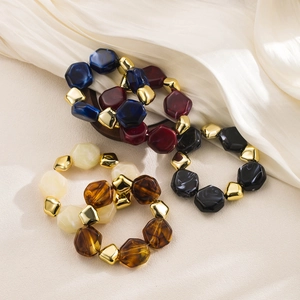 Detail of colorful chunky acrylic beaded bracelets with metallic gold accents