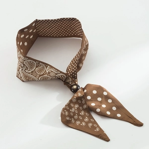 Dettaglio di sciarpa in seta con stampa paisley e pois con fibbia decorativa ad anello marrone