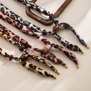 Detailed macro view of leopard print silk scarves with resin beads and metallic tips