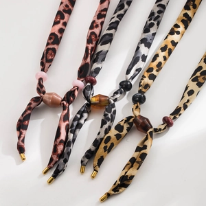 Detail of leopard print silk scarf necklaces with gold metal ends and resin beads