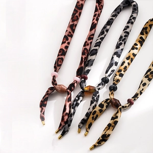 Detailed macro view of four leopard print scarves with decorative beads and metal tips