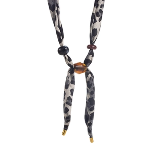 Detailed shot of leopard print scarf necklace with amber beads and gold metal tips