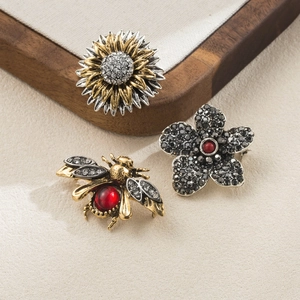 Macro shot of vintage style sunflower, bee and flower brooches with shiny crystals