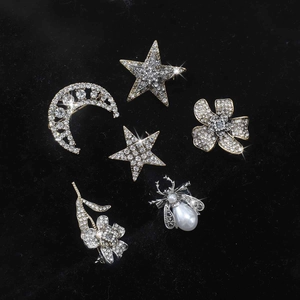 Sparkling rhinestone brooch set with moon, star, flower, and insect designs on black velvet