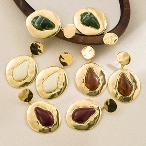 Detailed close-up of geometric gold earrings with hammered texture and colorful resin drops