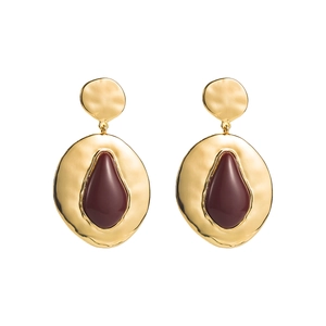 Detail view of gold hammered metal geometric earrings with burgundy teardrop enamel inlay