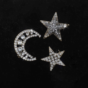 Detailed macro view of rhinestone moon and star brooches on black velvet background