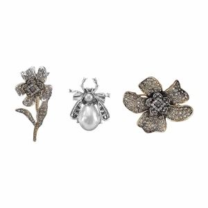 Detailed close-up of retro silver brooch set with rhinestones, pearls, and bee motifs