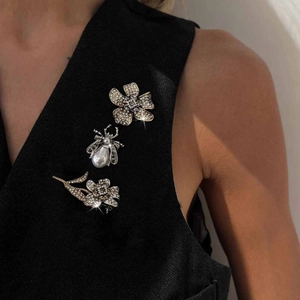 Three-piece rhinestone sunflower and beetle brooch set worn on a black waistcoat vest