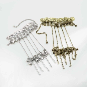 Detailed view of bohemian slave bracelets with vintage coins and bells in silver and bronze