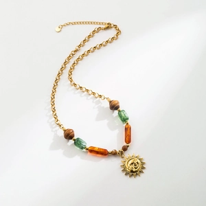 Detailed shot of vintage beaded necklace with gold chain and sun face pendant charms