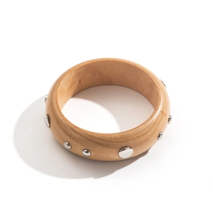 Gros plan détaillé d'un bracelet en bois marron orné de clous argentés sur fond blanc