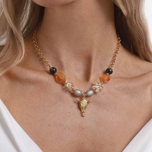 Vintage bohemian beaded necklace with gold chain and bull skull pendant on model