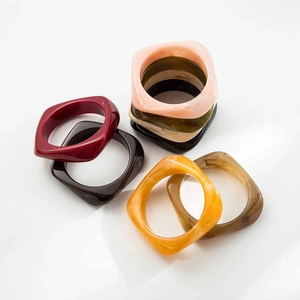 Vue macro de bracelets en résine empilés avec textures marbrées et finis ambrés