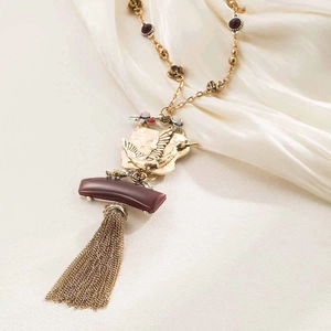 Detailed view of bohemian tassel pendant with intricate bird carving and red resin bead