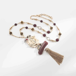 Detail of vintage geometric leaf pendant necklace with long metallic tassel and beads