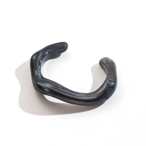 Macro detail of irregular C-shaped resin bracelet with grey marble ink texture and polished finish