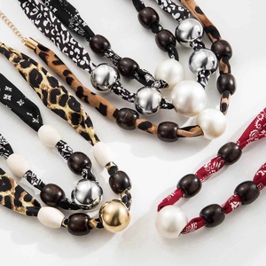 Detail of leopard print silk scarf necklace with vintage beads and wooden accents