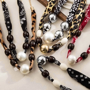 Close-up of leopard print fabric necklace with bohemian beads on stone texture background