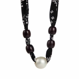Macro detail of leopard print silk scarf necklace with dark beads and white imitation pearl