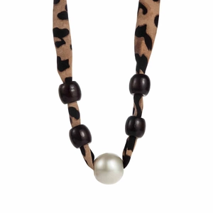 Detailed macro view of leopard print fabric strap with brown beads and a large white pearl
