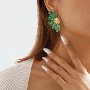 Detail of vintage flower stud earring with green enamel petals and golden core on model