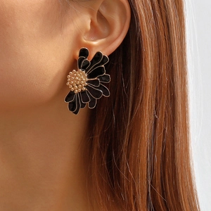 Close-up of elegant black enamel daisy earring with golden flower center on model