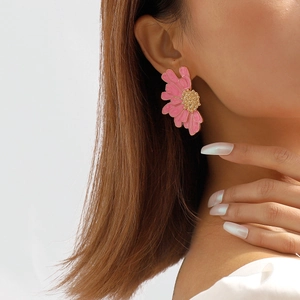Close-up of pink daisy stud earrings with gold center worn by a female model