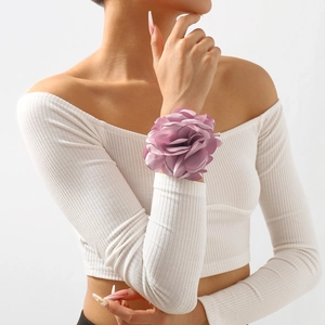 Detailansicht eines lila Seidenblumen-Armbands am Handgelenk mit weichem Lichteffekt