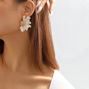Close-up of model wearing large white daisy flower earrings with gold-tone centers