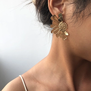 Close-up of vintage gold floral earring on ear with detailed metallic textured petals