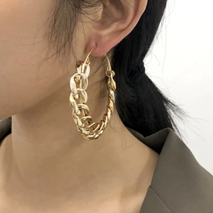 Punk style chunky golden chain hoop earrings worn by a model in a side profile view